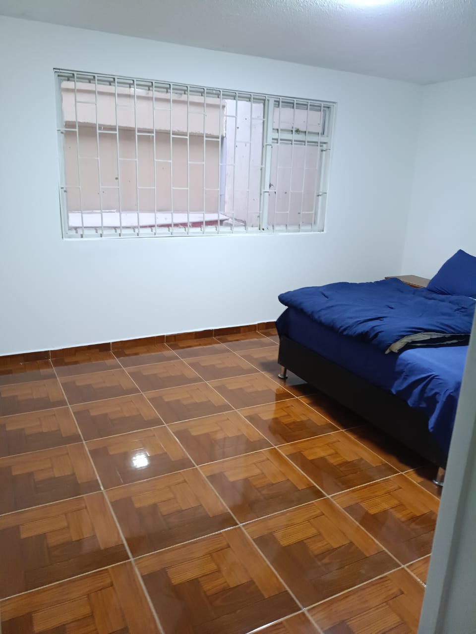 Habitación con cama y piso de madera